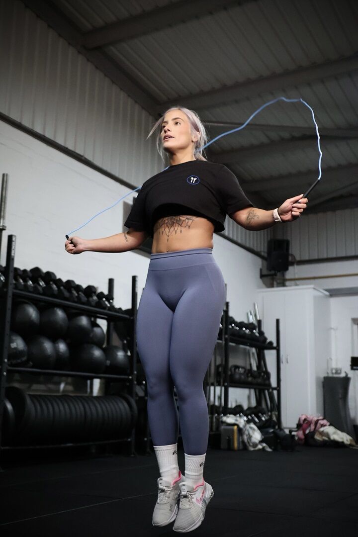 skipping rope woman in a gym skipping with a blue skipping rope