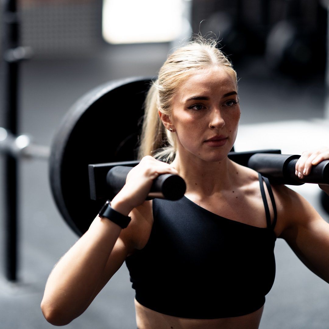 Hack 3 Woman performing a hack squat with the Forte Fitness hack squat attachment on her shoulders loaded with weigthts