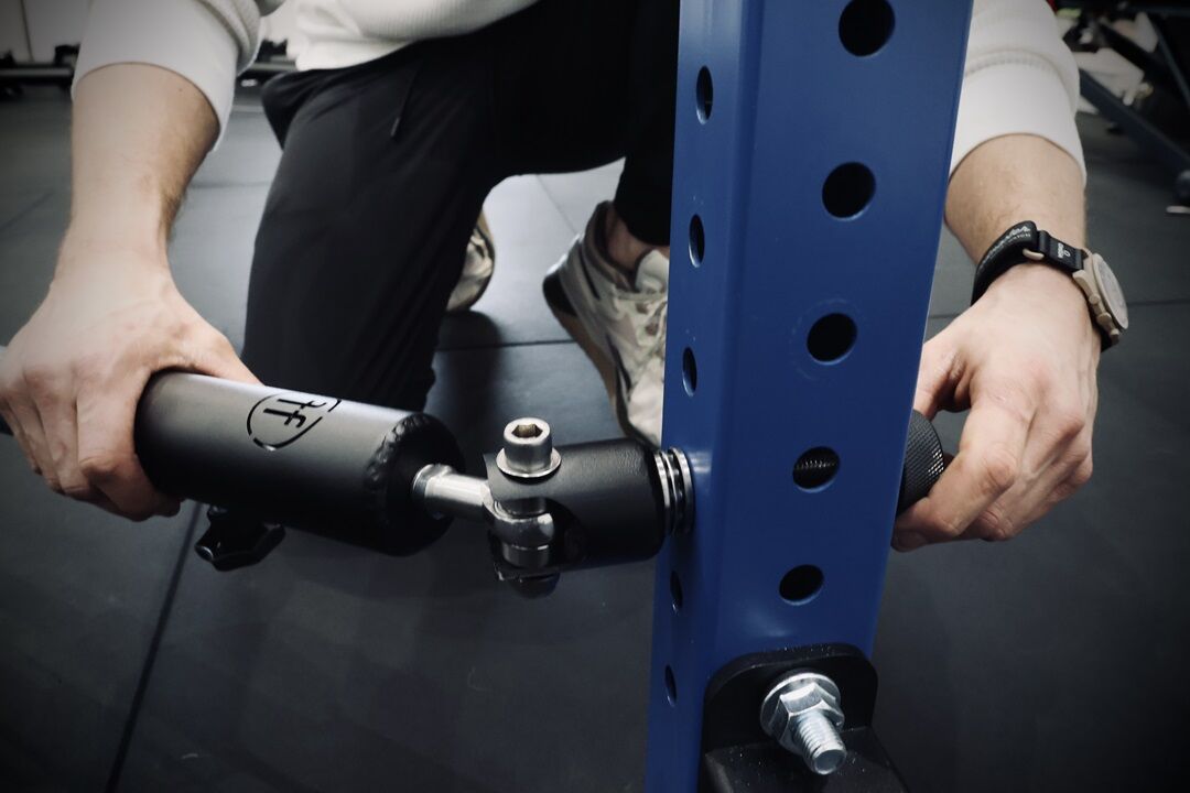 landmine attachment. man setting up a landmine attachment to a blue rack