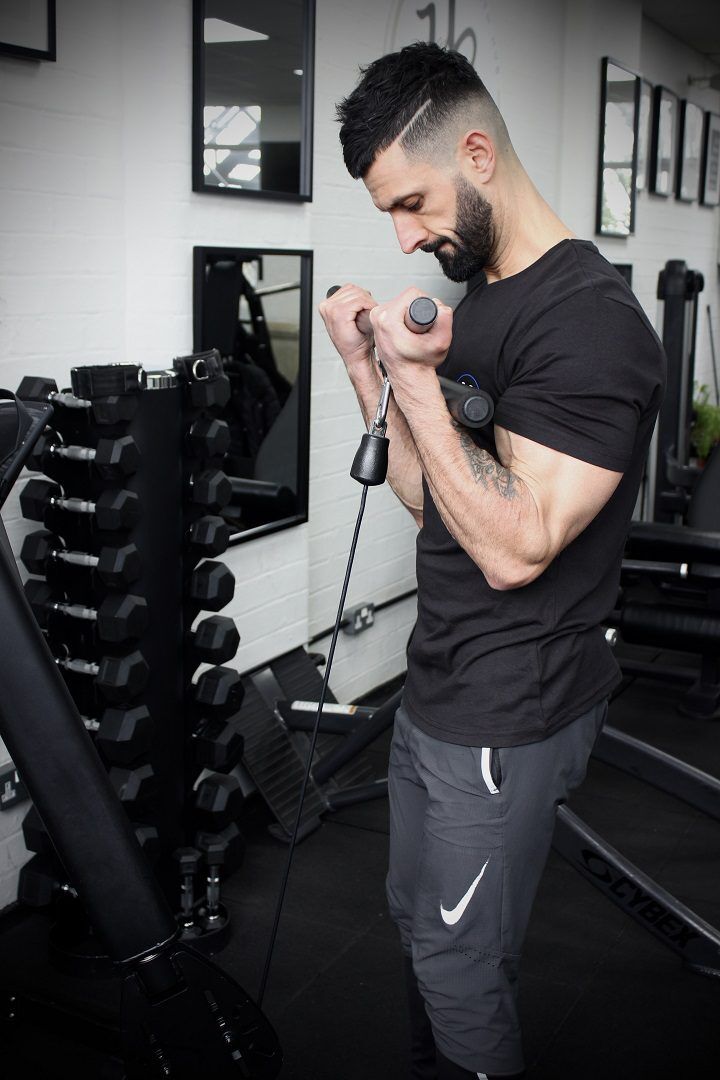 Curl Bar A man using the Forte Fitness curl bar. The picture is taken from a side-facing angle, showing the tension in muscles and pulling motion towards his face.