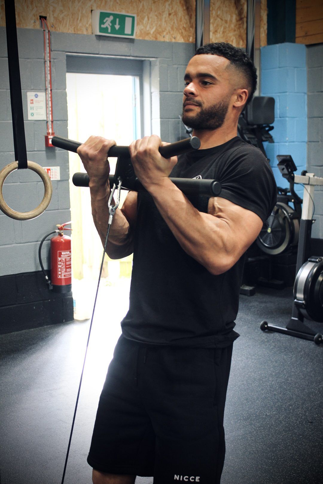 Bicep curl bar A man using the Forte Fitness curl bar from a front-facing angle. Tension in the arm muscles as the bar and cord are pulled towards his chin.