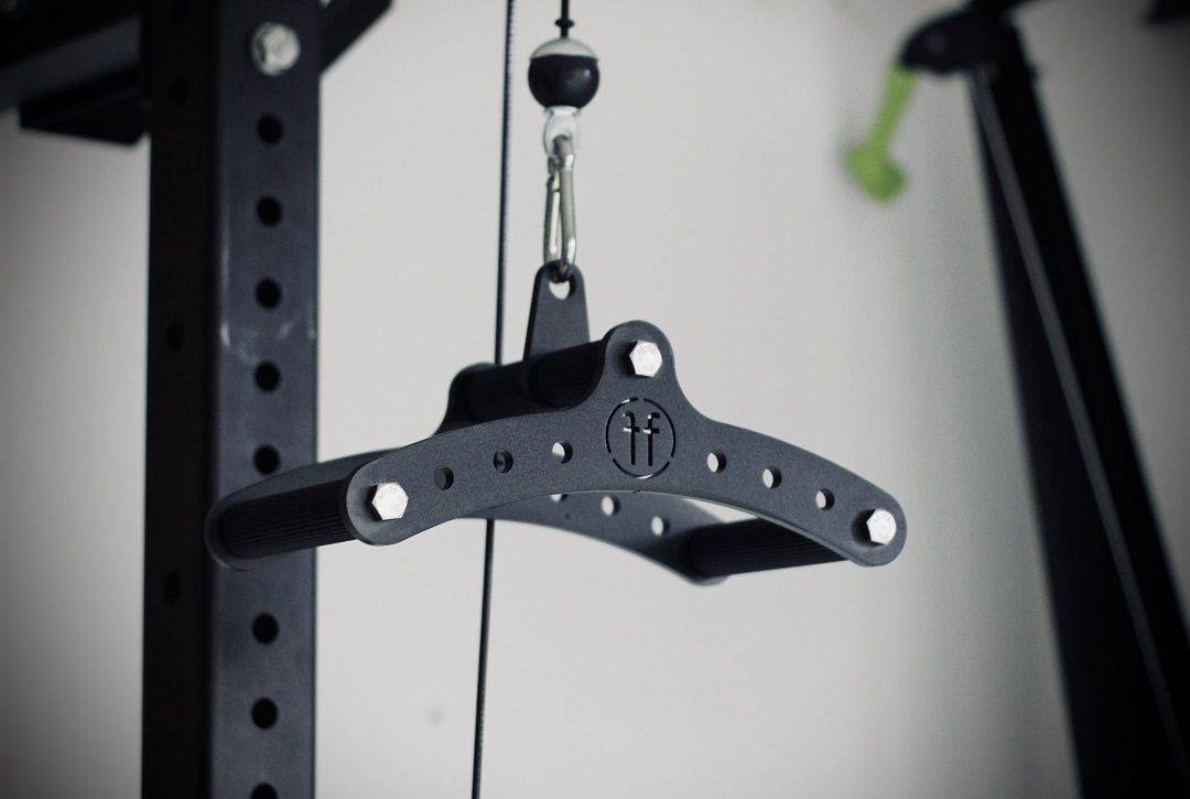 Cable Row Black Attached A black Forte Fitness cable row attachment, The picture is taken as close-up of the tool attached to a cable machine.