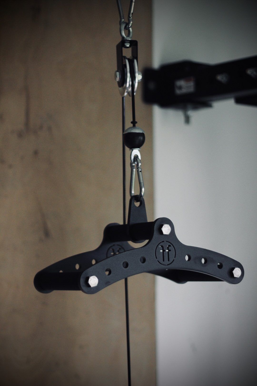 Cable row black 2 A Forte Fitness cable row attachment suspended in their air by wires, as it is attached to a cable row machine.