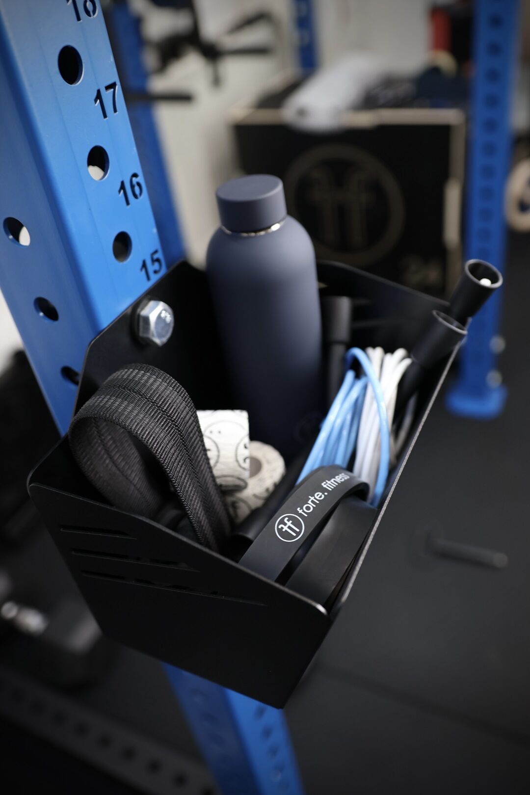 basket rack mounted chalk basket holding a bottle, resistance bands, lifting straps and skipping ropes