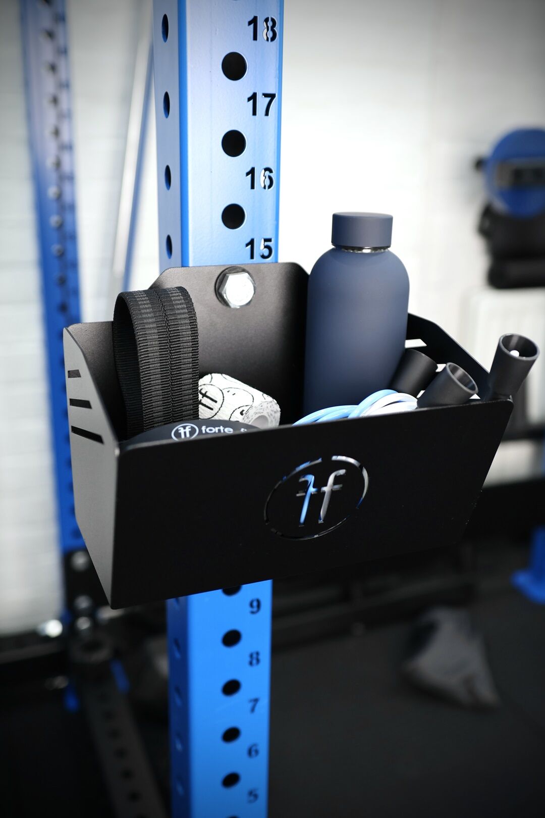 basket rack mounted chalk basket holding a bottle, resistance bands, lifting straps and skipping ropes